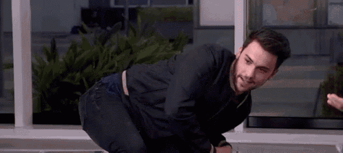 a man is kneeling down in front of a window in an office .