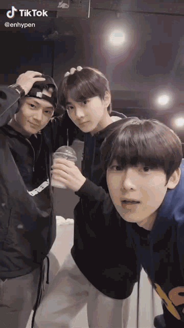 three young men are posing for a picture and one of them is sticking his tongue out