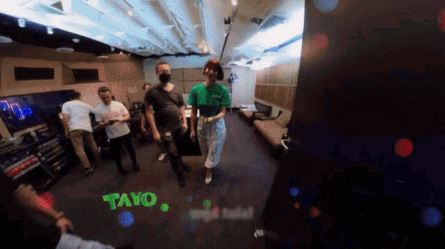 a group of people are standing in a room with the word tayo written on the floor