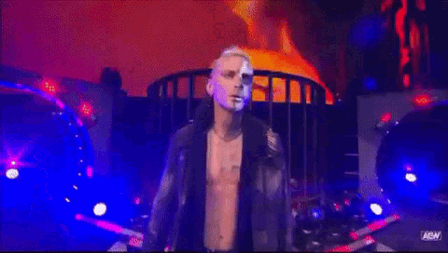 a man with a skull painted on his face is standing on a stage in a dark room .