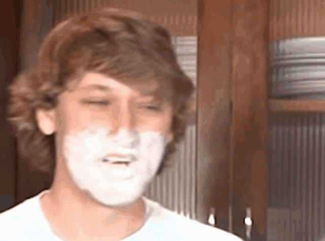 a young man with shaving cream on his face is looking at the camera