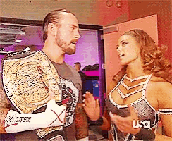 a man and a woman are standing next to each other and the woman is wearing a us wrestling belt