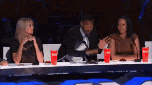 a man and two women are sitting at a table with cups of soda .