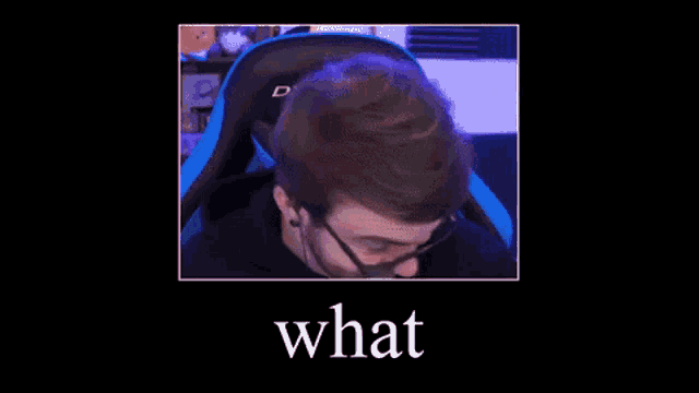 a man with a beard and glasses is sitting in a chair with the words `` what '' below him .