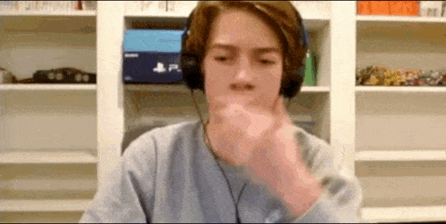 a young man wearing headphones is making a funny face while sitting at a desk .