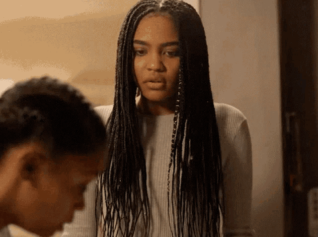 a woman with braids is looking at another woman 's face .