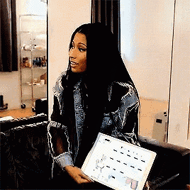 a woman in a denim jacket is sitting on a couch holding a piece of paper .