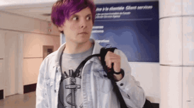 a man with purple hair is standing in front of a sign for client services