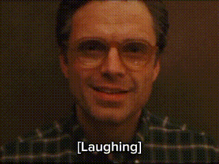 a man wearing glasses is smiling and laughing with the words laughing written below him .