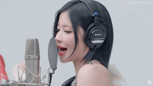 a woman wearing a pair of sony headphones sings into a microphone