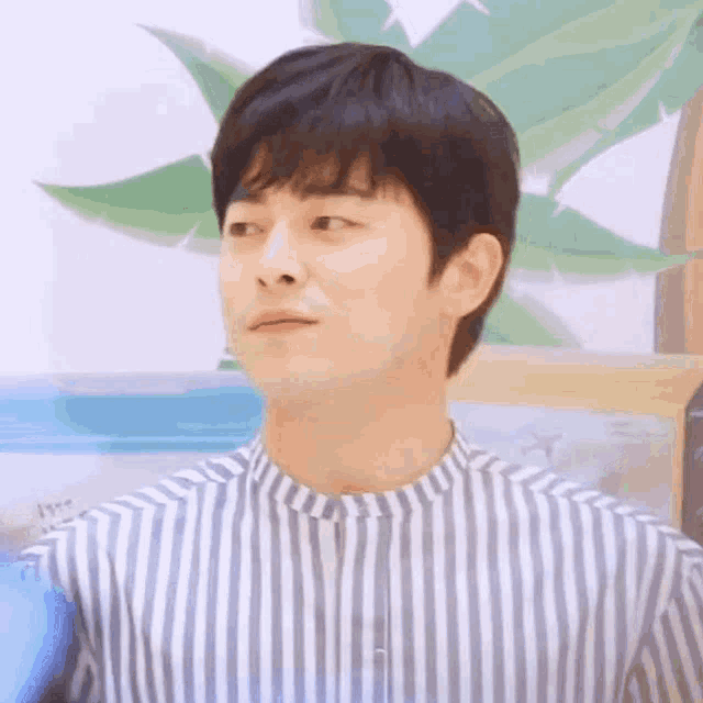 a close up of a man wearing a striped shirt making a funny face