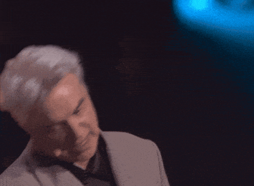 a man in a suit is speaking into a microphone in a dark room