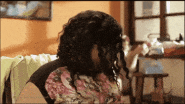 a woman with curly hair is sitting on a couch in a living room