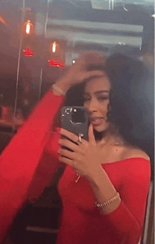 a woman in a red dress is taking a selfie in front of a mirror with her phone .