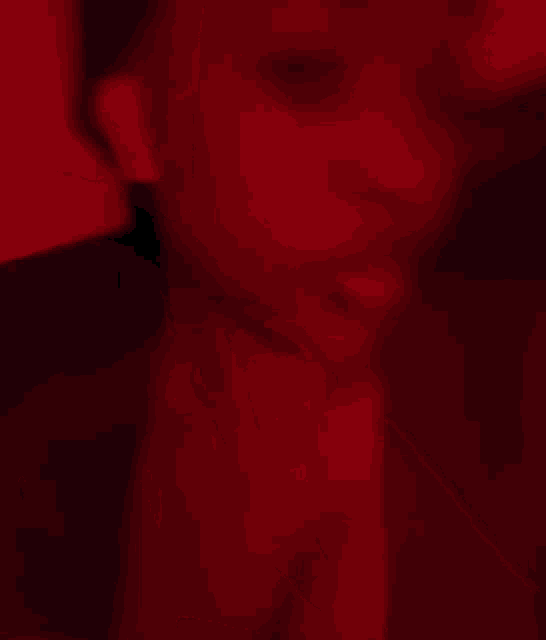 a person is laying in a dark room with a red light behind them .