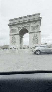 a car is driving in front of a triumphal arch