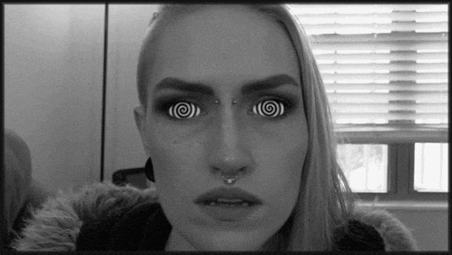 a woman with hypnotic eyes and a nose ring is looking at the camera in a black and white photo .