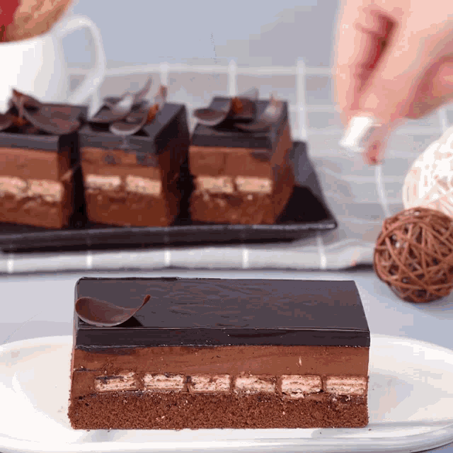 a piece of chocolate cake on a white plate with other pieces