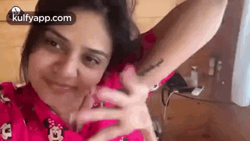 a woman is taking a selfie with her hands outstretched and a tattoo on her arm .