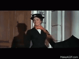 a woman in a hat and scarf is holding an umbrella in a room .
