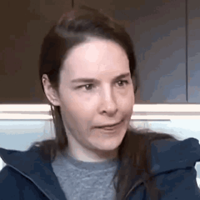 a close up of a woman wearing a blue jacket and a gray shirt .