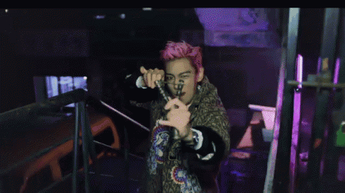 a man with pink hair is holding a cell phone
