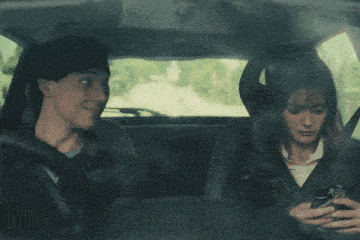 a man and a woman are sitting in a car smiling