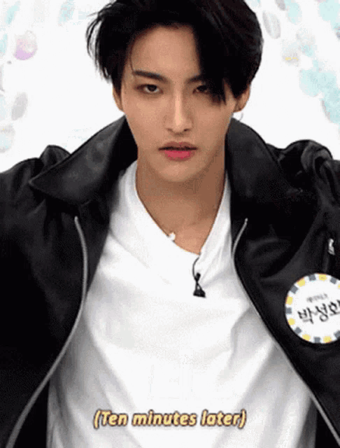 a young man wearing a white shirt and a black leather jacket says " ten minutes later "