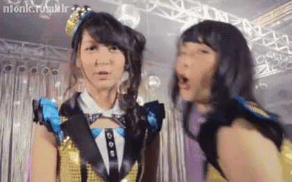 two young women are standing next to each other on a stage .