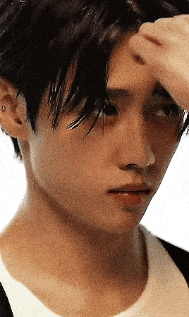 a close up of a young man 's face with his hand on his head .