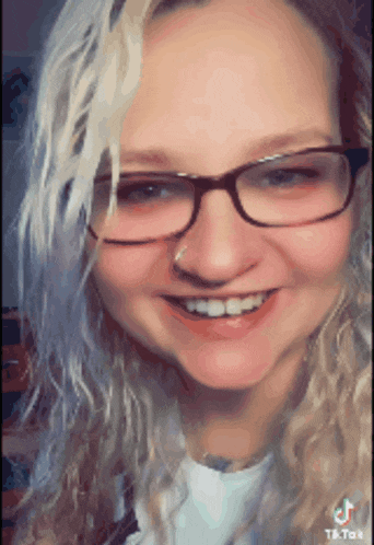 a woman with glasses and a nose ring smiles for the camera