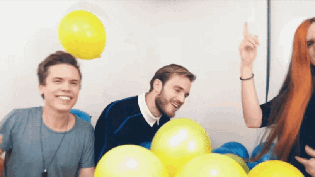 three people are playing with balloons and one of them is pointing up