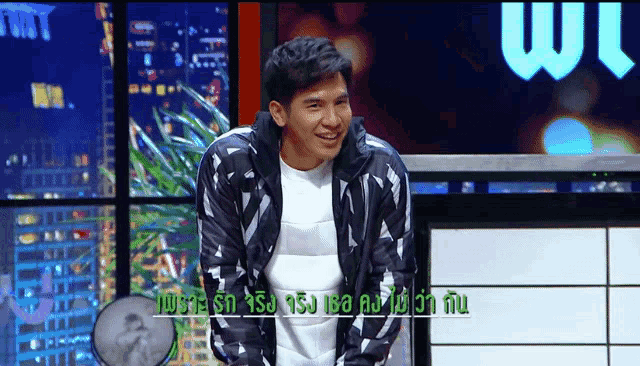 a man wearing a black and white jacket is smiling in front of a sign that says win