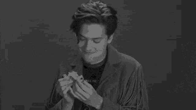 a black and white photo of a young man wearing a fringed jacket and a black shirt .