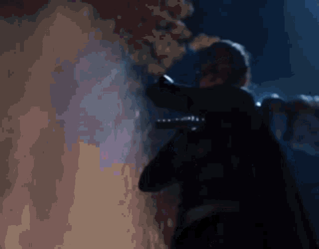 a blurry picture of a man standing in front of a wall holding a gun .