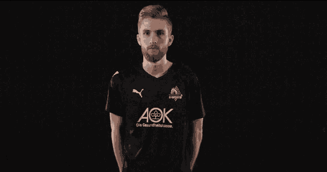 a man wearing a black aok shirt stands with his hands on his hips