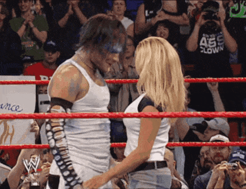 a man and a woman are standing in a wrestling ring with a sign that says ance