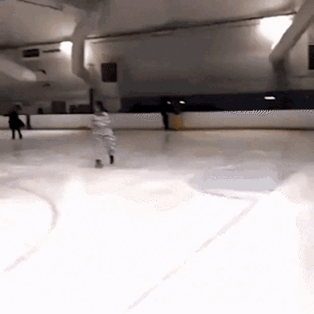 a person is ice skating on a rink in a dimly lit room