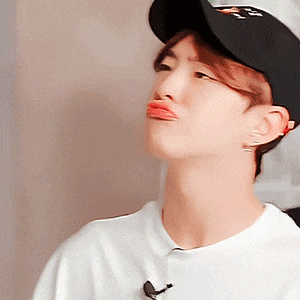 a young man wearing a baseball cap and a white shirt is making a funny face .