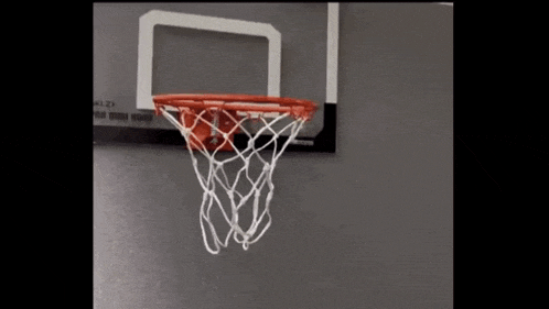 a basketball is going through a basketball hoop on a wall ..