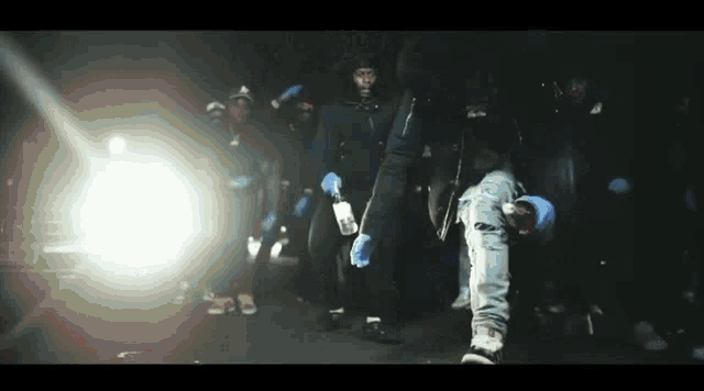 a group of people are standing in a dark room holding bottles of alcohol