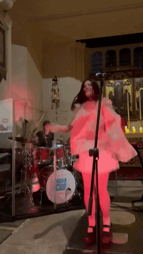 a woman singing in front of a drum set that says nova cup on it