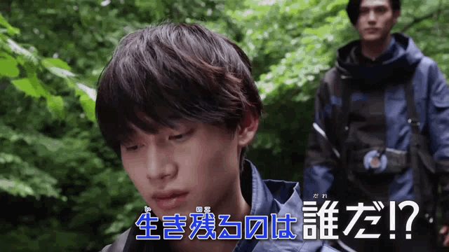 a man in a blue jacket stands next to another man in a black jacket in a forest ..
