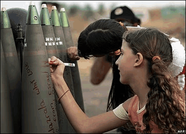 two girls are writing on a bunch of bullets with a marker