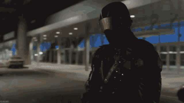 a man wearing a helmet and goggles is standing in front of a building
