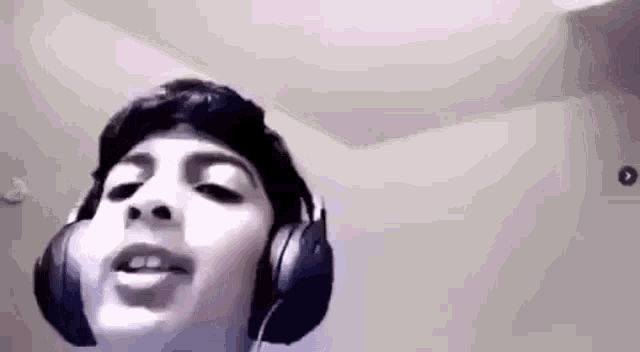 a boy wearing headphones is singing into a microphone .