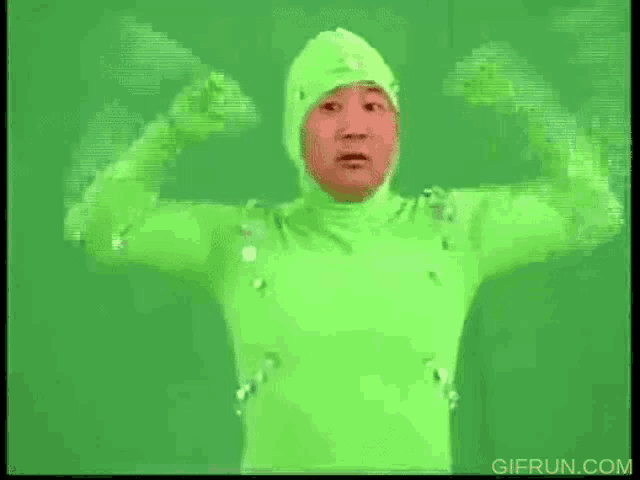 a man in a green suit is flexing his muscles on a green background .