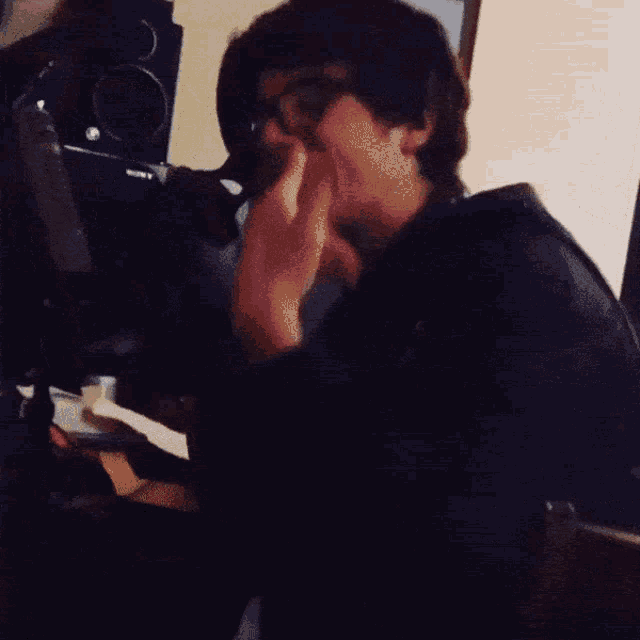 a man in a black shirt is eating something in a room