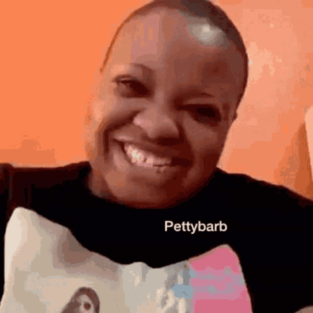 a woman is smiling and making a funny face while wearing a t-shirt that says pettybarb .