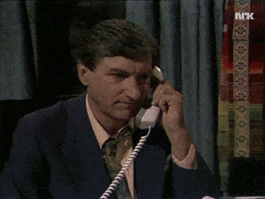 a man in a suit is talking on a telephone with the letters nk on the bottom right
